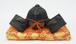 Miniatura de capacete em bronze de Samurai japonês sobre almofada. Medidas 10 x 20 cm.